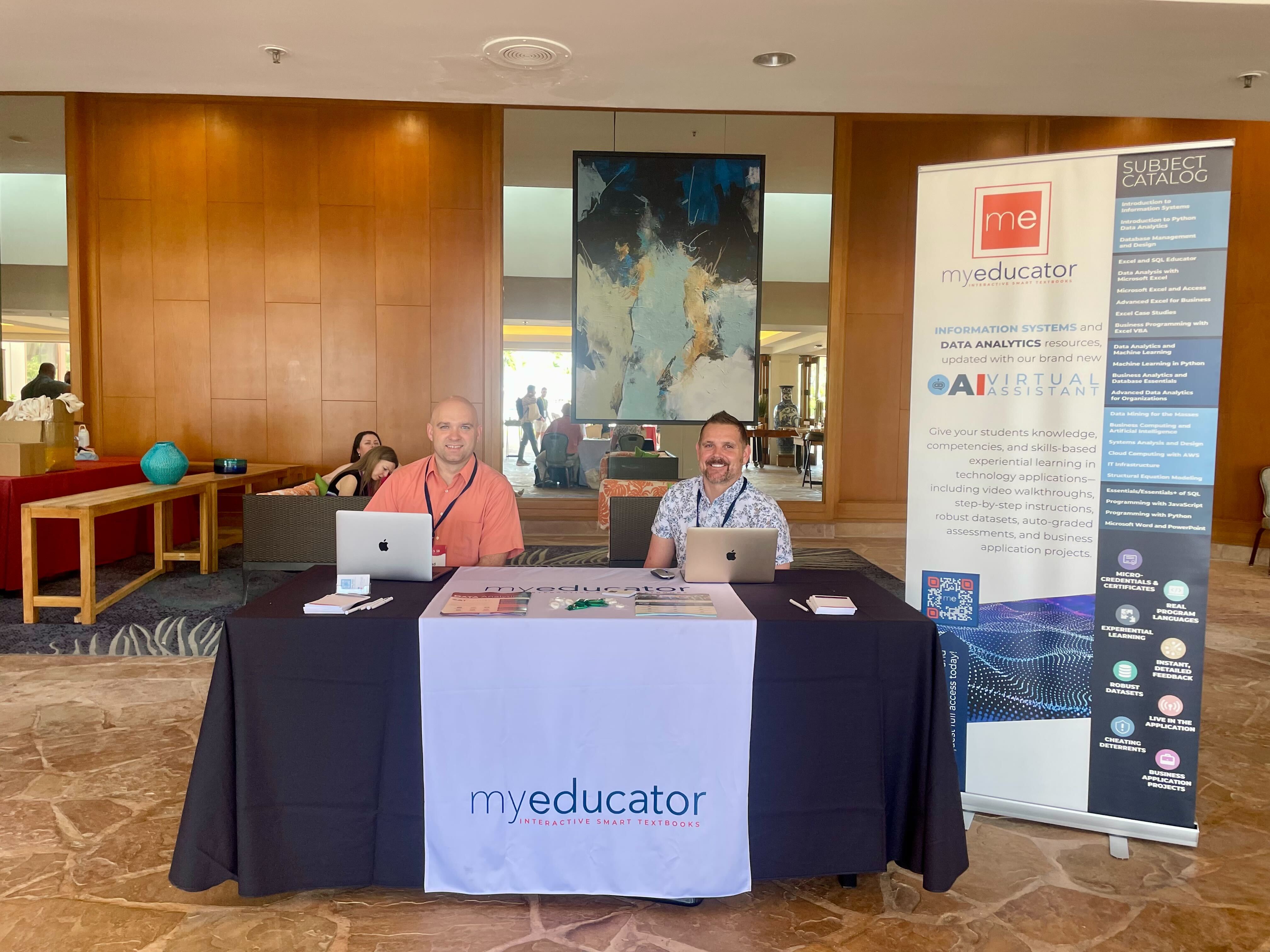 Scotty and Brad from the Outside Sales Team, sitting at a booth at an education conference at Waikoloa Village, Big Island, HI.